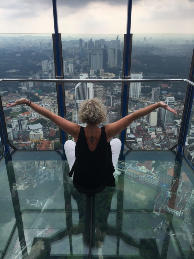 Christie Adams in a glass box looking out over Singapore vista