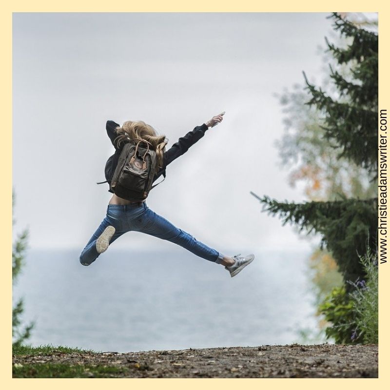 A woman jumping in the air, with a backpack, to show how happy she is