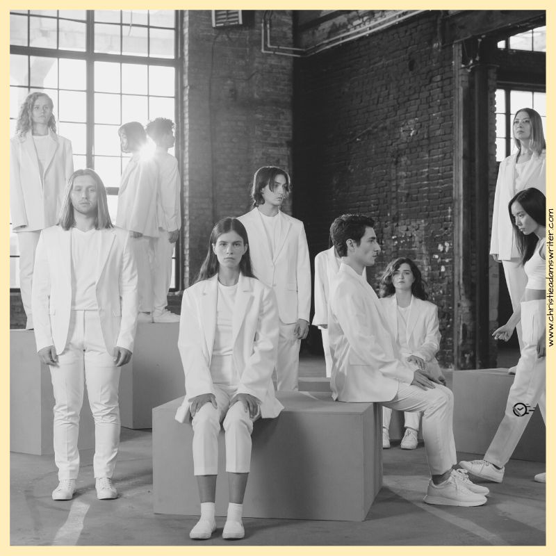 People in white suits standing and seated on boxes